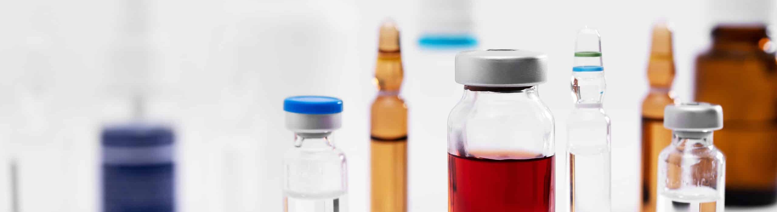 A closeup shot of different glass vials with liquids on a white surface at a lab